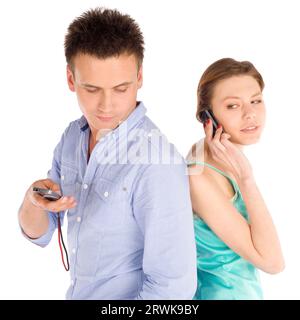Young casual couple debout dos à dos, femme parlant au téléphone, l'homme contrôle sms, isolé sur fond blanc Banque D'Images