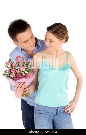 Happy young attractive casual couple dans l'amour, l'homme donnant des fleurs à une femme, isolated on white Banque D'Images