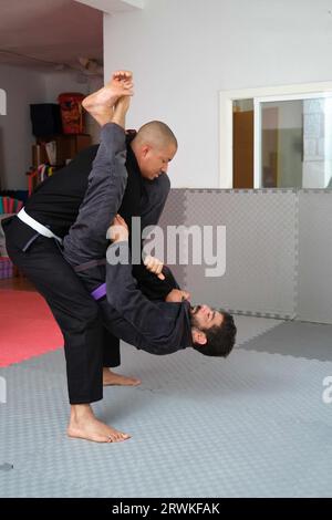 Deux hommes pratiquant la lutte brésilienne Jiu-Jitsu à l'école. Formation BJJ. Banque D'Images