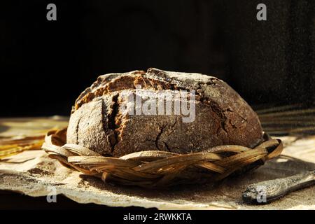 Pain traditionnel fraîchement cuit dans une pincée de farine. Pain de seigle sans levure sur la table de la cuisine, gros plan. Fond alimentaire. Style rustique. Banque D'Images