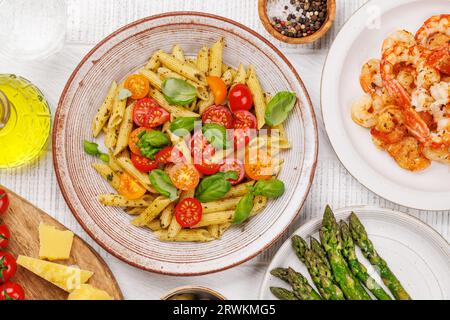 Une délicieuse assiette de pâtes italiennes ornée de tomates fraîches et de feuilles de basilic aromatiques. Pose à plat Banque D'Images