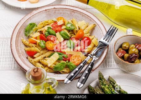 Une délicieuse assiette de pâtes italiennes ornée de tomates fraîches et de feuilles de basilic aromatiques, d'asperges grillées et de crevettes Banque D'Images