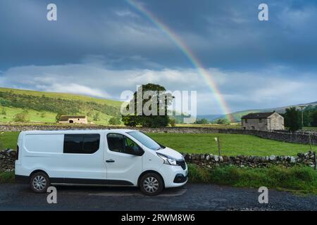Un camping-car blanc garé sous un arc-en-ciel sous une pluie légère, Littondale, North Yorkshire, Royaume-Uni Banque D'Images