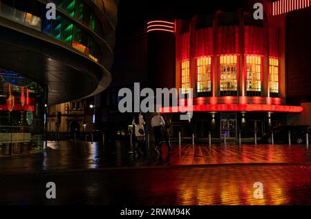 Une soirée à Leicester avec le club Athena illuminé des lumières rouges et jaunes et colorées dans le Curve Theatre. Lumière réfléchie sur chaussée mouillée Banque D'Images