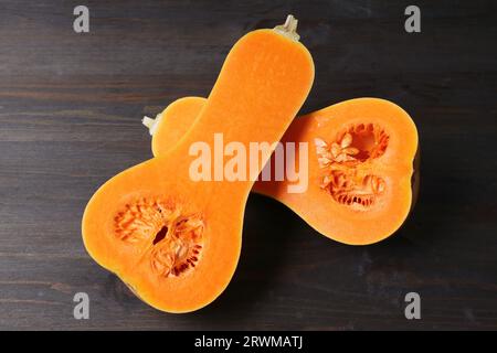 Purée de noyer cendré mûr Couper en deux montrant une chair orange vibrante Isolé sur une table en bois noir Banque D'Images