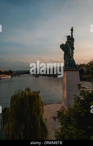 Une image à couper le souffle de l'emblématique Statue de la liberté à Paris contre un ciel pittoresque de coucher de soleil Banque D'Images
