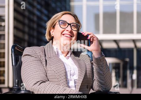 femme d'affaires utilisant un fauteuil roulant parlant par téléphone Banque D'Images