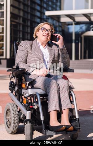 femme d'affaires utilisant un fauteuil roulant parlant par téléphone Banque D'Images