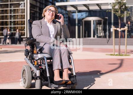 femme d'affaires utilisant un fauteuil roulant parlant par téléphone Banque D'Images