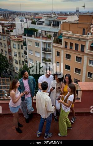 Vue verticale du groupe supérieur des amis heureux réunis célébrant le vin à la fête penthouse. Contexte. Banque D'Images