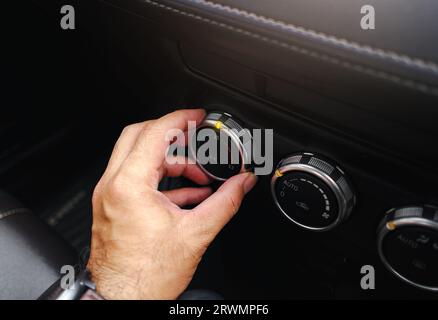 La main du conducteur règle la température du climatiseur de voiture dans la voiture, la main tourner le commutateur pour sélectionner le niveau de température. Banque D'Images