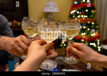 griller avec la famille le soir de noël avec champagne avec arbre de noël en arrière-plan. Banque D'Images