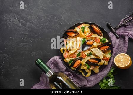 Spaghetti vongole, pâtes italiennes aux fruits de mer avec des palourdes et des moules, dans une assiette avec des herbes et un verre de vin blanc sur fond de pierre rustique. Traditionnel I Banque D'Images