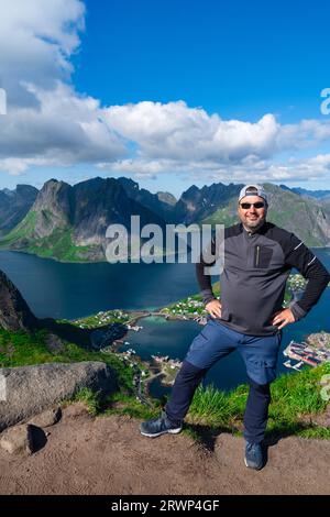 Randonneur détendu bénéficie d'une vue imprenable sur les fjords et les sommets des îles Lofoten, en Norvège Banque D'Images