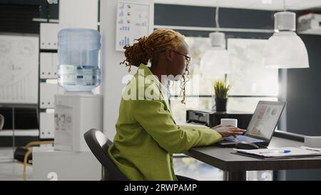 Femme d'affaires malade travaillant avec mal de tête dans le bureau, se sentant malade et stressée dans l'espace de coworking. Assistante exécutive souffrant de migraine douloureuse et étant en tension, agence d'affaires. Banque D'Images