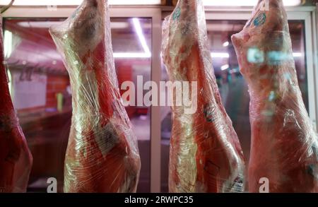 Des carcasses de porc bouchées sont suspendues dans une boucherie. Banque D'Images