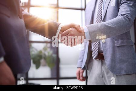 Gros plan de deux hommes d'affaires qui se secouent la main au bureau Banque D'Images