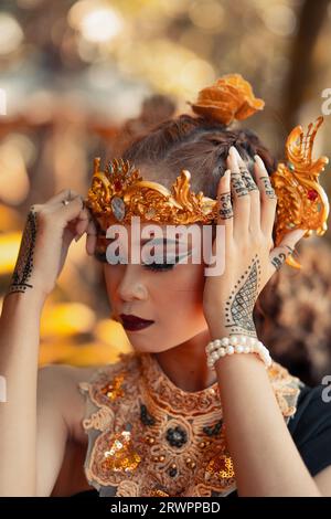femme ancienne dans sa couronne d'or et collier d'or pose dans sa robe noire à l'intérieur de la forêt pendant la lumière du jour Banque D'Images