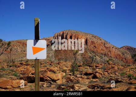 panneau directionnel orange ou flèche sur un poteau sur un sentier de randonnée dans le désert en territoire du nord, australie Banque D'Images