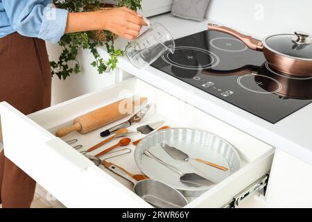 Femme mettant la tasse à mesurer dans le tiroir de cuisine Banque D'Images