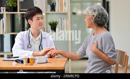 Un médecin asiatique professionnel parle avec une vieille patiente dans une salle d'examen d'un hôpital. Contrôle médical, concept de santé Banque D'Images