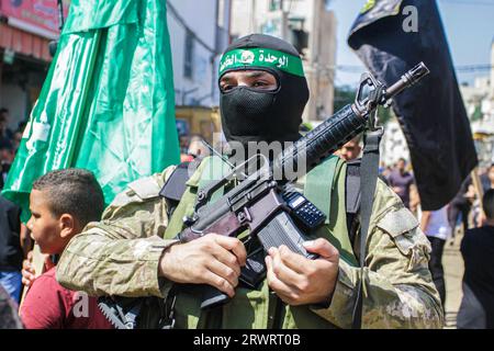 Un tireur masqué prend part aux funérailles de Mahmoud al-Sadi, 23 ans, Mahmoud Ararawi, 24 ans, et ATA Yasser Musa, 29 ans, drapés dans le drapeau du Hamas et du Jihad islamique lors de leurs funérailles dans le camp de réfugiés de Djénine, en Cisjordanie. Les responsables palestiniens de la santé disent que le nombre de morts au cours d'une journée de combats entre Israël et les Palestiniens en Cisjordanie occupée et dans la bande de Gaza est passé à six, dont quatre à Djénine. L'armée a déclaré que les forces ont effectué une frappe rare mardi avec un drone suicide pendant l'opération et ont échangé des tirs avec des hommes armés à Djénine. Banque D'Images