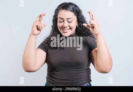 Jeune femme souriante faisant un vœu avec un geste plein d'espoir. Fille latine croisant les doigts faisant un vœu Banque D'Images