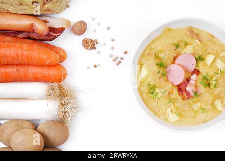 Soupe de pommes de terre fraîchement cuite dans un bol à soupe à côté des ingrédients frais Banque D'Images