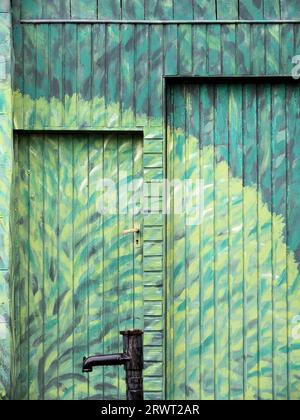 Peintures murales, arbre de différentes couleurs vertes, sur la maison et la porte, devant elle une installation de fontaine Banque D'Images