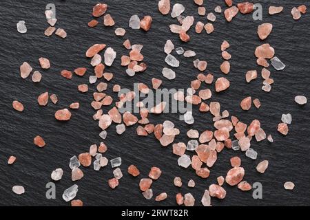 Sel rose de l'Himalaya utilisé pour épice et condiment dans la cuisine sur fond d'ardoise noire. Banque D'Images