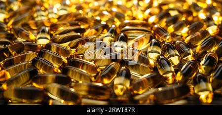 Beaucoup de vitamine D jaune, huile de poisson, capsules d'oméga-3 à la lumière du soleil sur la table. Huile de poisson molle, suppléments de vitamine D capsules sur fond en bois Banque D'Images