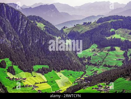 Vue plongeante sur les terres agricoles, les maisons, les arbres et les montagnes dans la vallée de l'Alpbachtal, Tyrol, Alpes autrichiennes. Banque D'Images