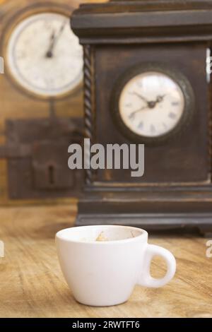 tasse de café avec deux vieilles horloges murales en arrière-plan Banque D'Images