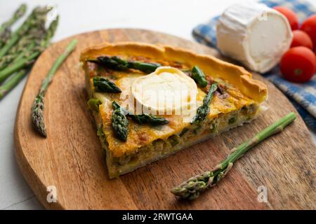 Quiche à la française avec asperges vertes, œufs et tranches de fromage de chèvre. Banque D'Images