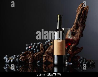 Bouteille de vin rouge avec vieille étiquette vide. En arrière-plan, de vieux accrochages altérés et des raisins bleus. Banque D'Images