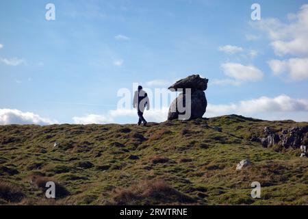 Homme marchant près d'un rocher équilibré sur le sommet de 'Lee Gate High Mark' près de Mastiles Lane près de Malham, parc national des Yorkshire Dales, Angleterre, Royaume-Uni Banque D'Images