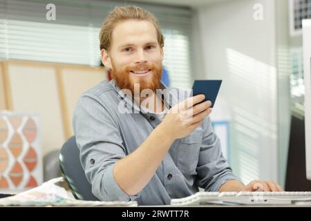 le designer masculin était assis au bureau tenant l'échantillon de couleur Banque D'Images