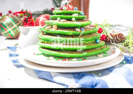 Pile de crêpes vertes pour le petit déjeuner, comme un arbre de Noël avec des saupoudrés de sucre.Petit déjeuner de Noël festif sur table décorée de Noël et de nouvel an Banque D'Images