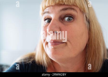 Portrait femme d'âge moyen, blonde, grimacant dans le miroir avant Banque D'Images