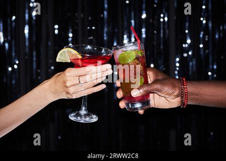 Gros plan de deux personnes tenant des cocktails sur fond de fête scintillant, espace de copie Banque D'Images