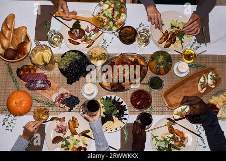 Image de fond de vue de dessus des gens à la table de dîner de fête pour Thanksgiving appréciant des plats rôtis, espace de copie Banque D'Images
