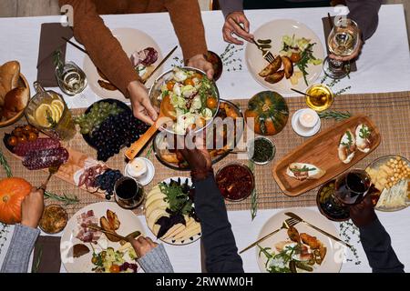 Image de fond de vue de dessus des gens mangeant à la table de dîner de fête pour Thanksgiving remettant des plats rôtis, espace de copie Banque D'Images