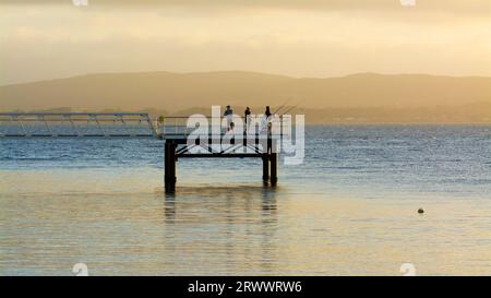 Les gens sur une jetée pêchant près du coucher du soleil à Princess Royal Harbour, Albany, Australie occidentale Banque D'Images
