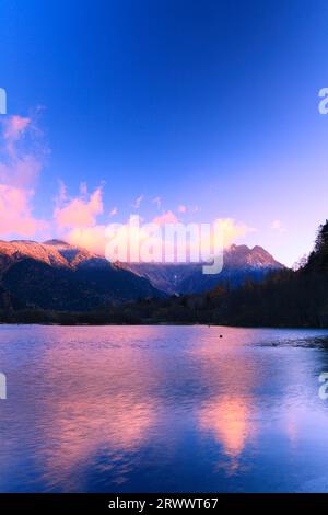 La chaîne de montagnes Hotaka avec des feuilles d'automne, de la glace brumeuse et des nuages lumineux matinaux de Taisho Pond à Kamikochi en automne Banque D'Images