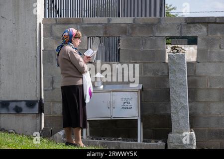 Une femme juive orthodoxe prie sur une pierre tombale d'un cimetière juif dans le comté d'Orange, New York. Banque D'Images