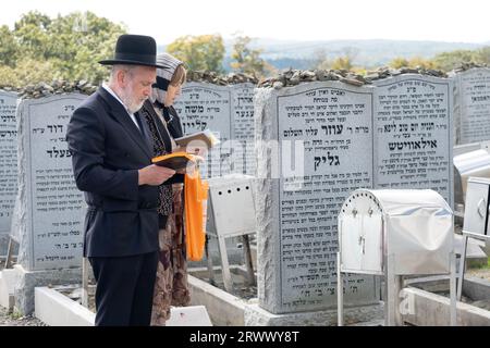 Un couple hasidique prie sur la pierre tombale d'un membre de la famille au vieux cimetière Satmar à Kiryas Joel, à Monroe, New York. Banque D'Images