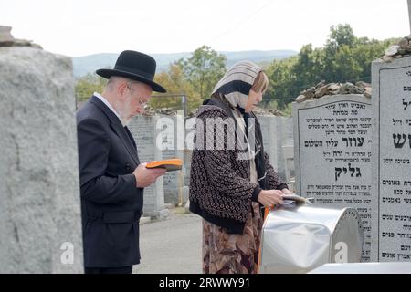 Un couple hasidique prie sur la pierre tombale d'un membre de la famille au vieux cimetière Satmar à Kiryas Joel, à Monroe, New York. Banque D'Images