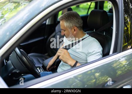 Homme caucasien d'âge moyen attacher des ceintures de sécurité dans la voiture Banque D'Images