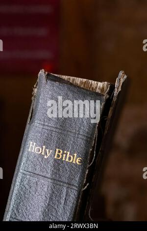 Un vieux livre de la Sainte Bible. La reliure Bibles est cassée et son capot avant est suspendu. Les mots Sainte Bible sont marqués sur la colonne vertébrale des livres Banque D'Images