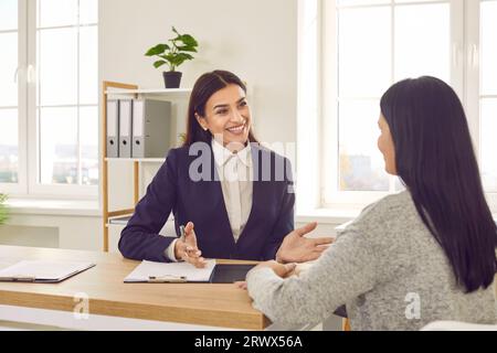 Femme d'affaires souriante parlant avec le client pendant la réunion formelle dans le bureau Banque D'Images